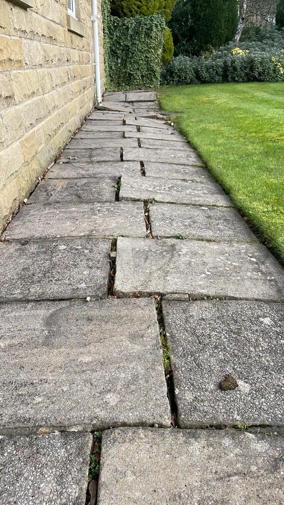 Uneven stone path with separated flags beside a house